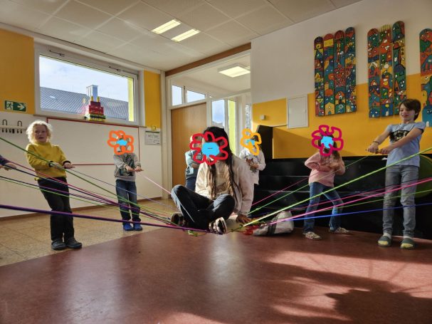 Kinder halten ein Kind an einem Seilenetz hoch 